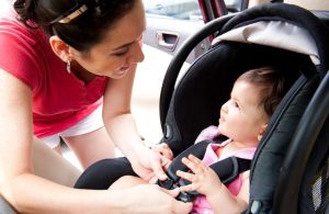 Mother buckling her child in a safety carseat