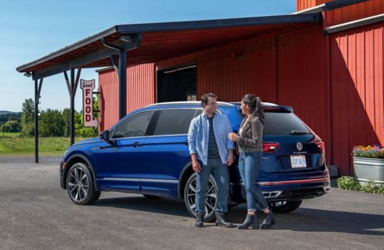 Couple Standing Behind a Blue 2024 Volkswagen Tiguan