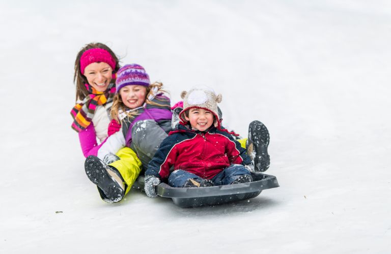 Kids and Mom on a Toboggan on a Sledding Hill