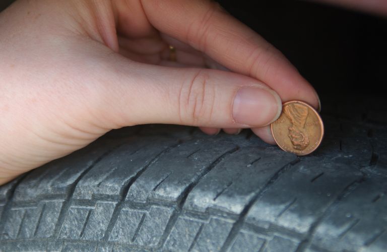 Close Up of Person Using a Penny to Check Tire Tread Depth
