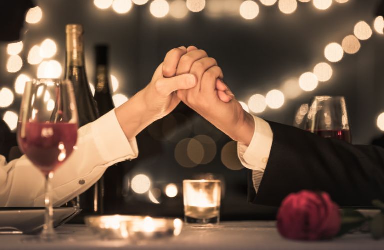 Two People Holding Hands Across a Dinner Table