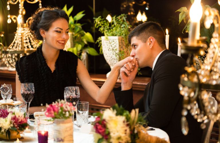 Man Kissing Woman's Hand at a Dinner Table
