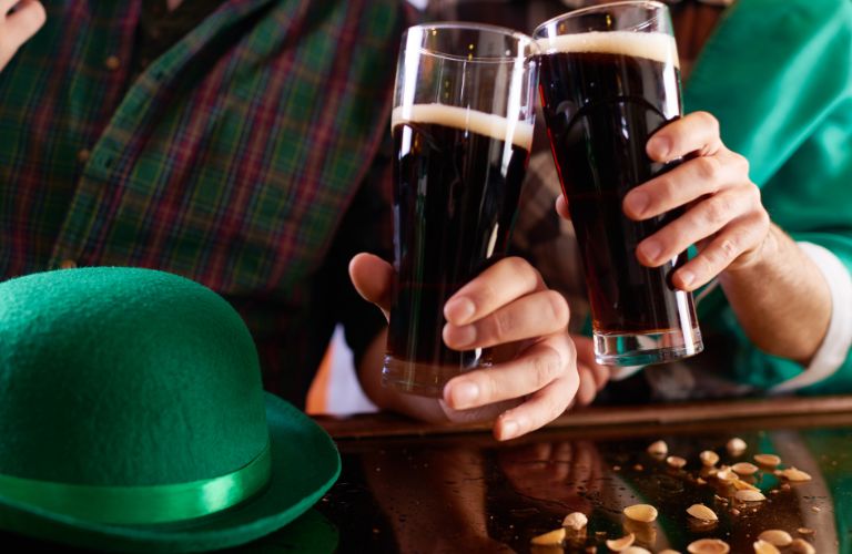 People Cheers with Glasses of Guinness and Green Leprechaun Hat